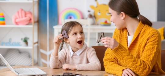 Speech therapist working with cute girl in clinic