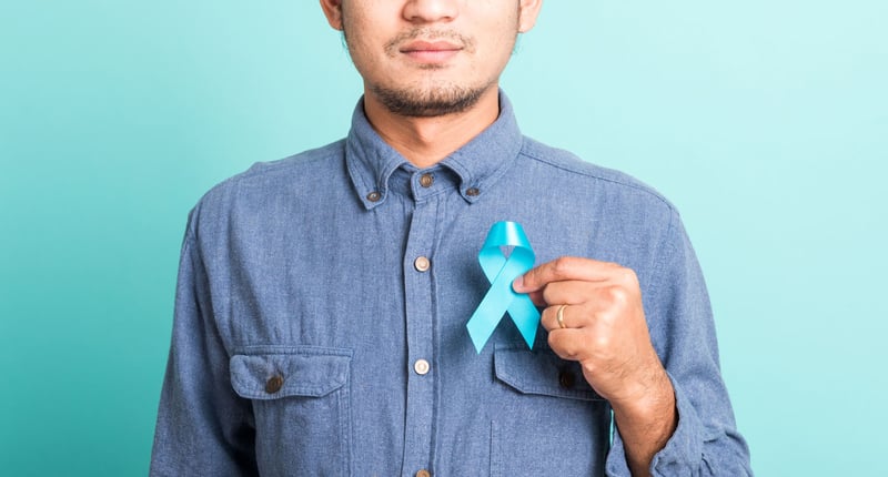 Asian man holding a blue ribbon symbolizing Prostate Cancer